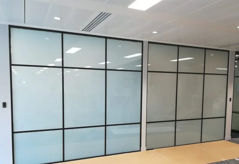 Black-framed office glass partition with frosted smart film panels