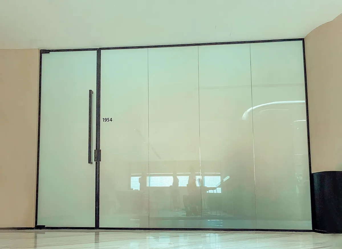 Frosted switchable glass partition with a full-height glass door in an office
