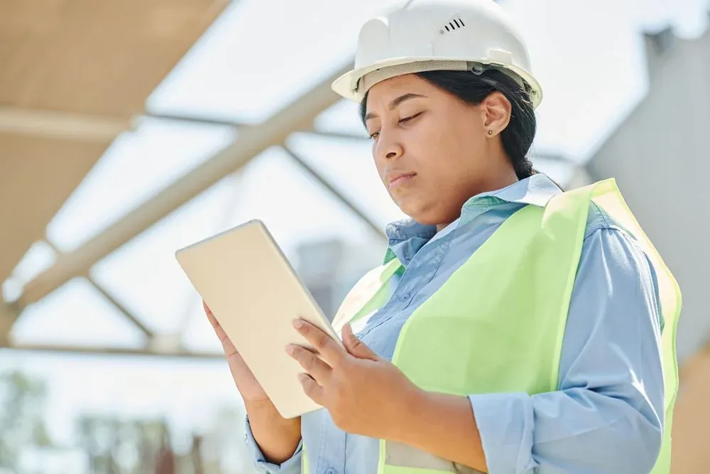 Site engineer in a hard hat checking project details on a tablet