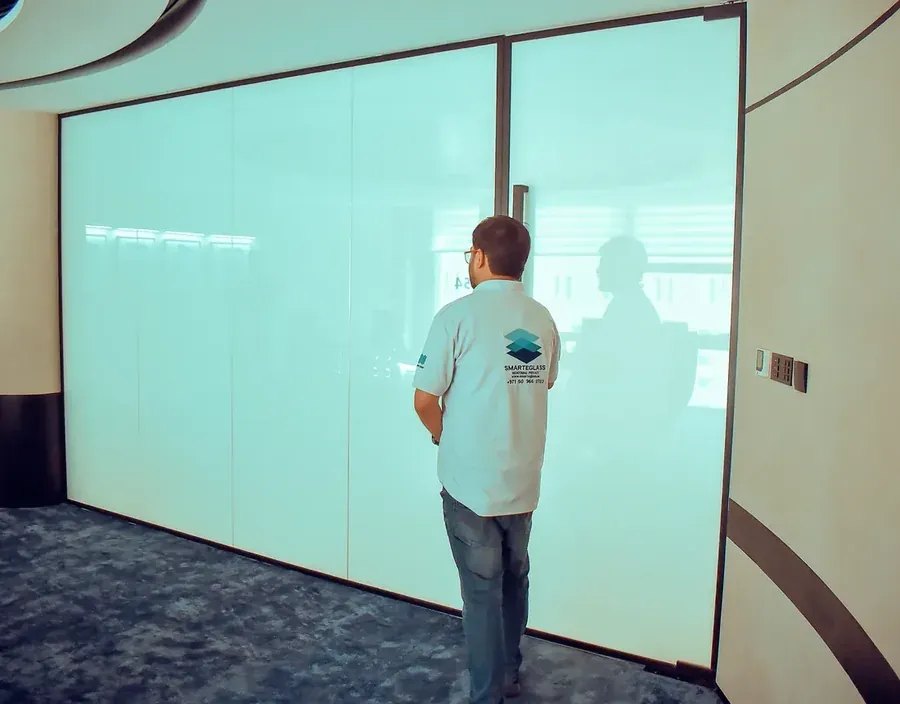 SEG technician beside a frosted switchable smart glass partition in an office