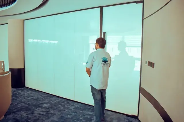 SEG technician beside a glass wall switched to frosted with Self-Adhesive Smart Film