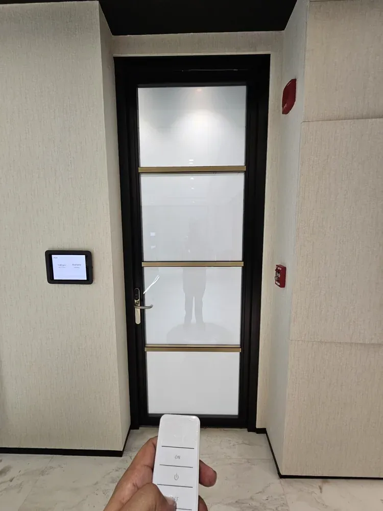 Remote control switching a smart glass door panel, with a wall control panel beside the door